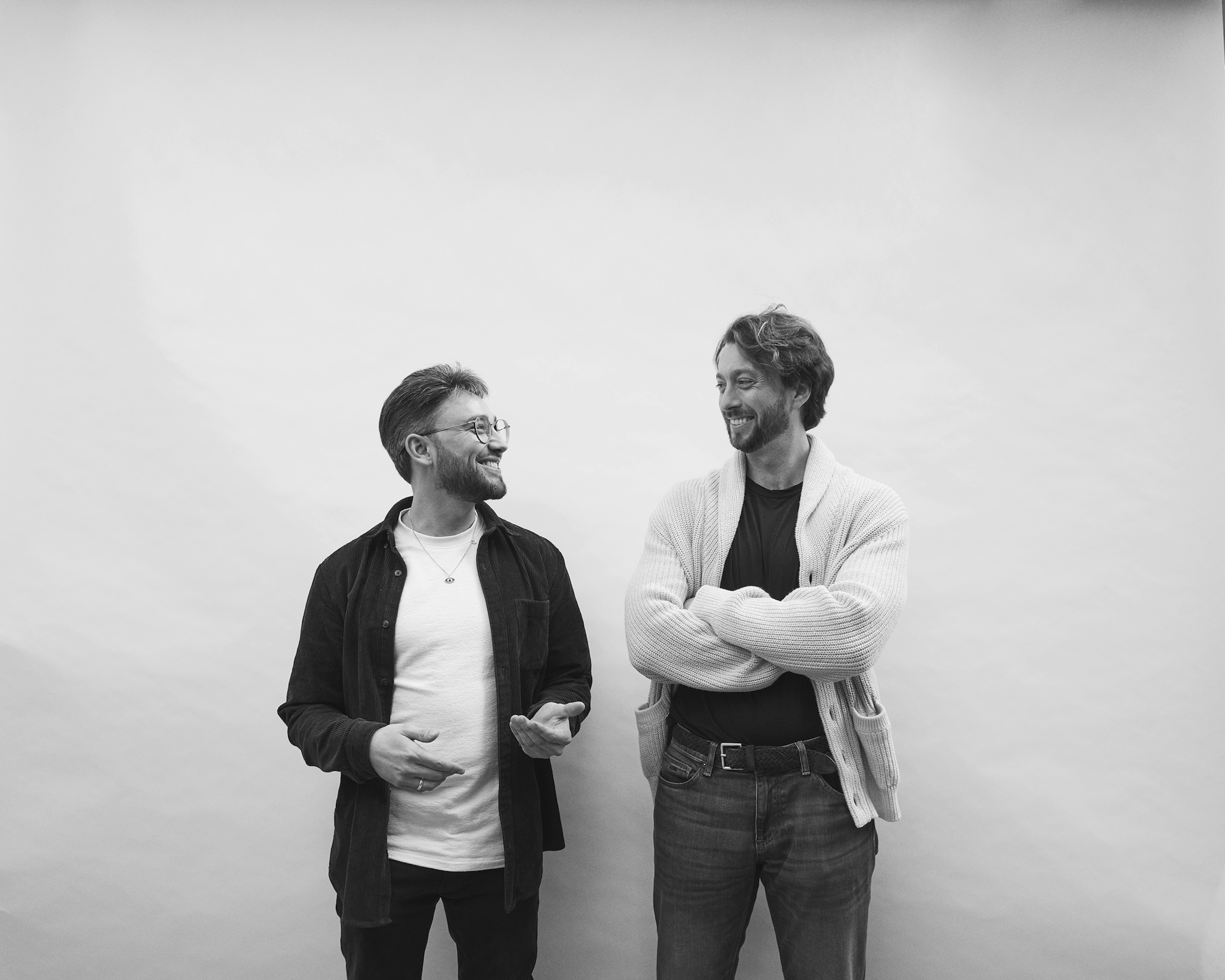 A black and white image of Wonder cofounders smiling at each other.