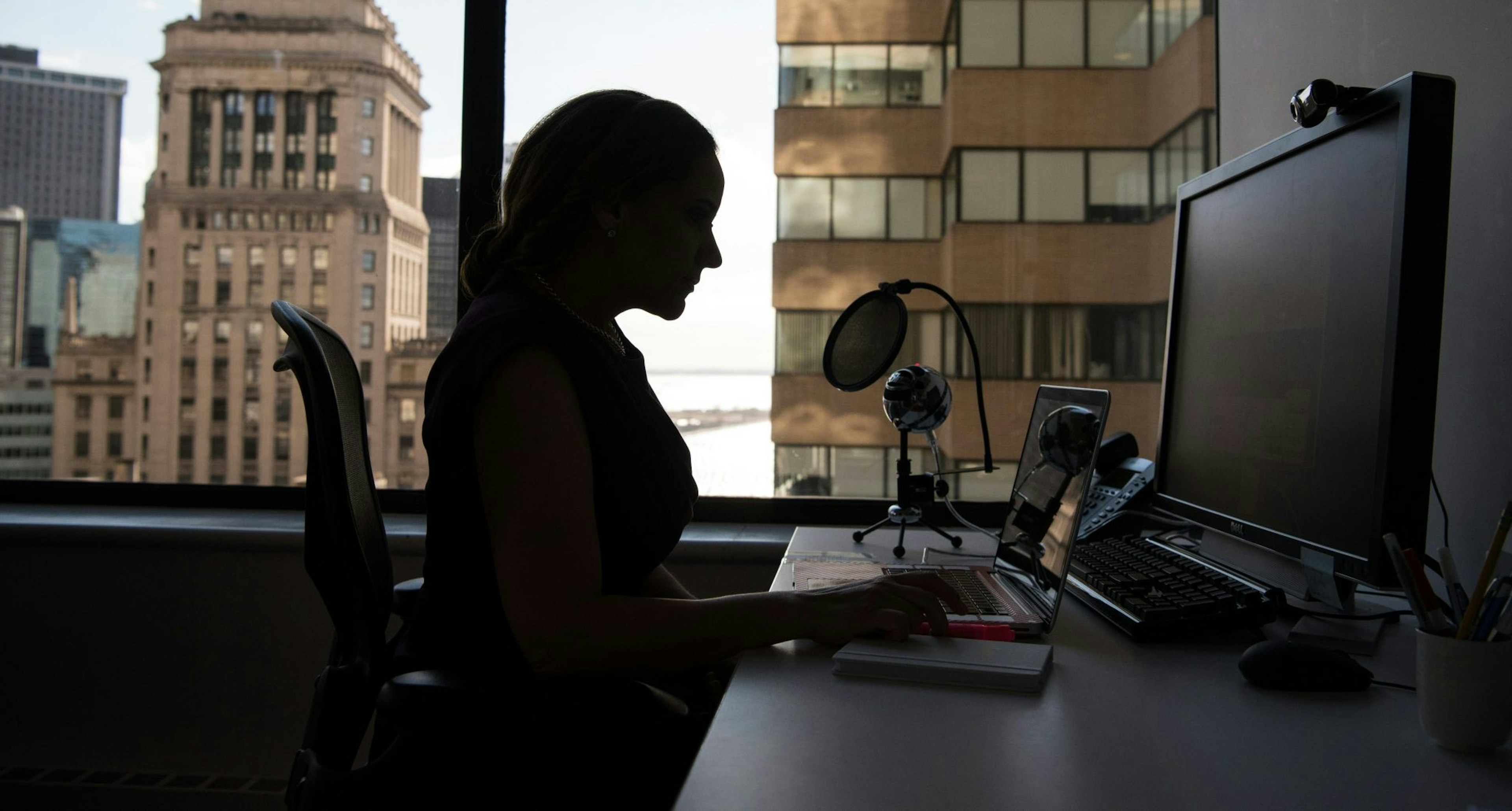 A woman sat at her desk at her computer screen