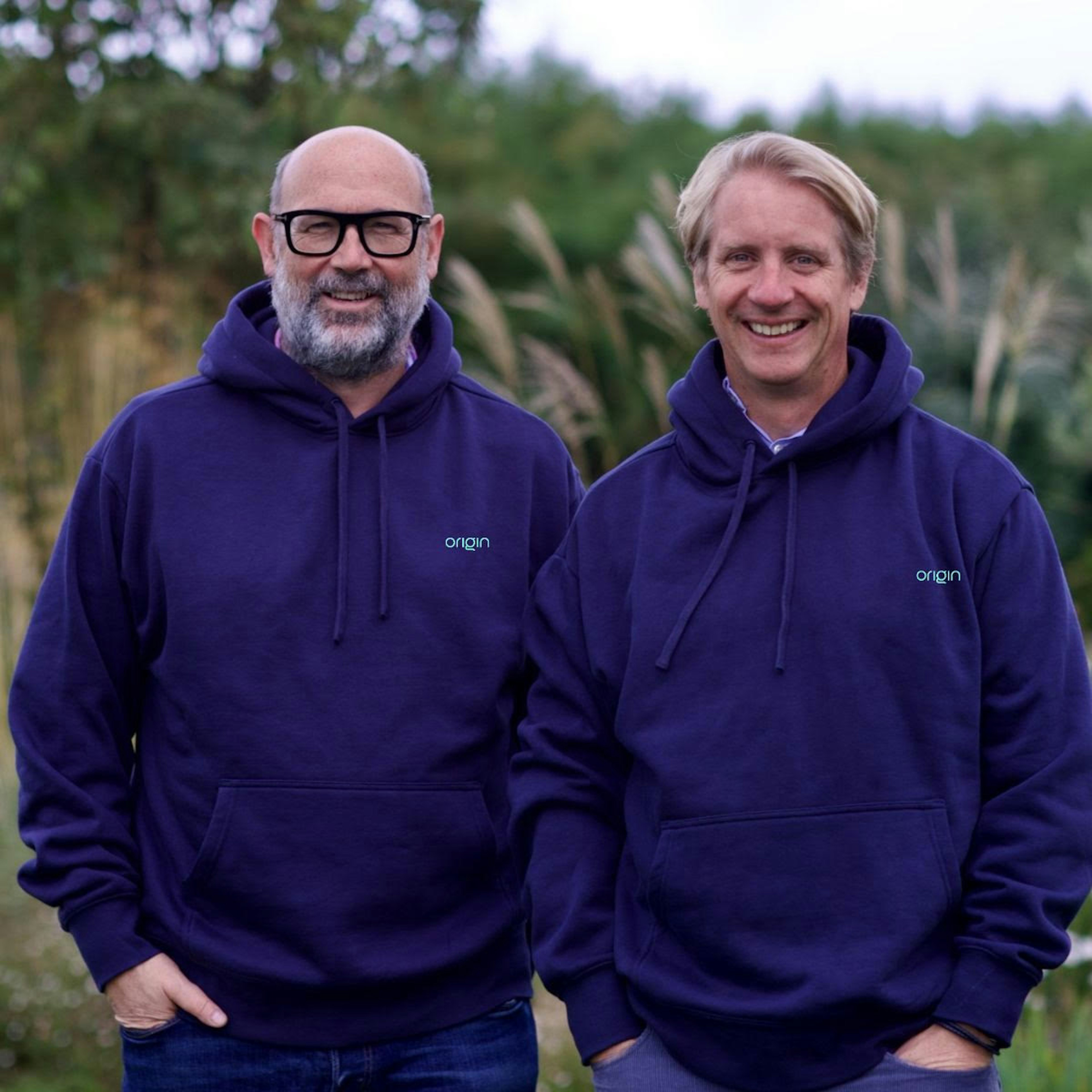 Origin cofounders in purple hoodies, posing outside.