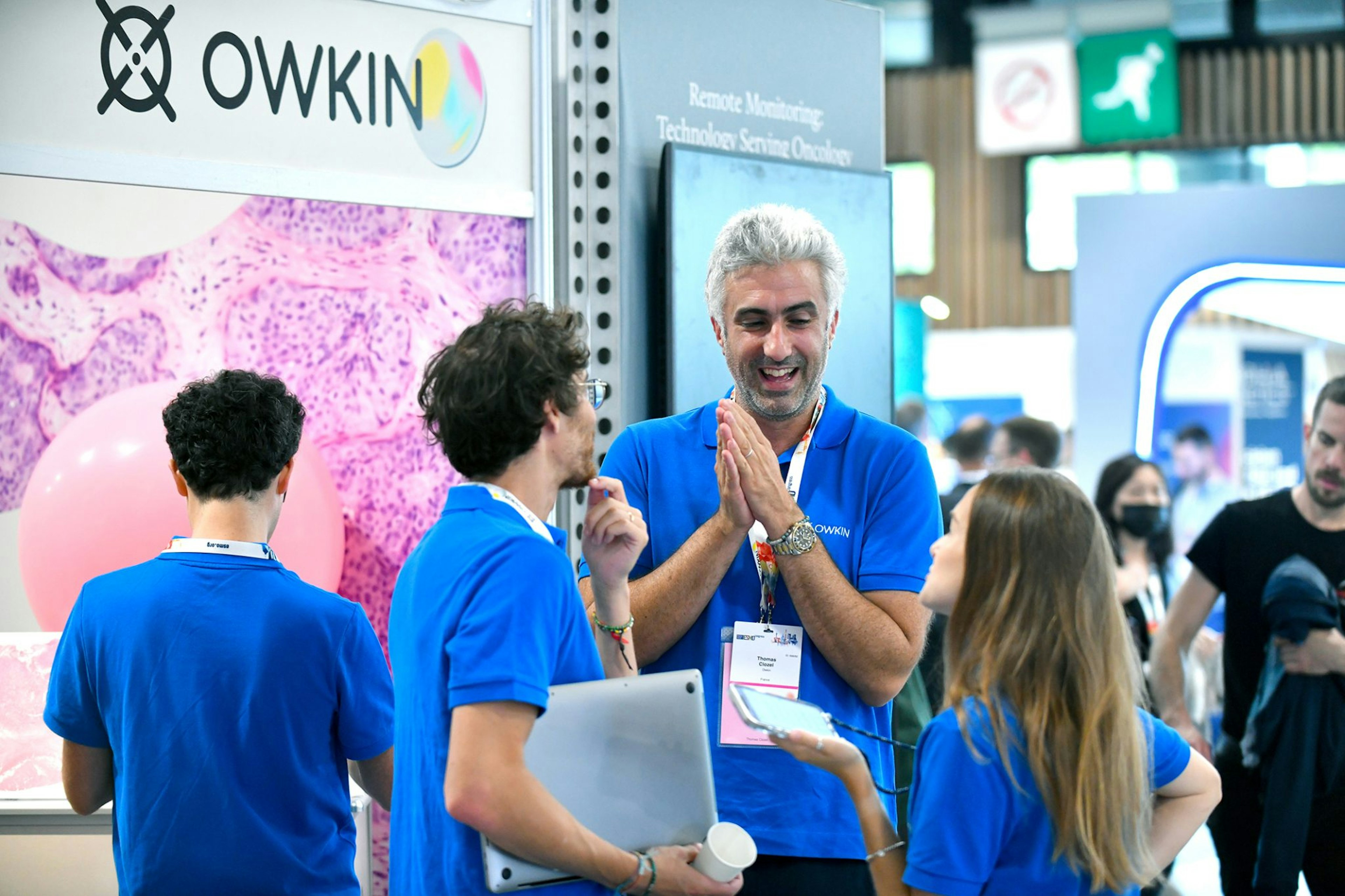 A picture of Owkin's founder and CEO Thomas Clozel talking with two colleagues at a conference