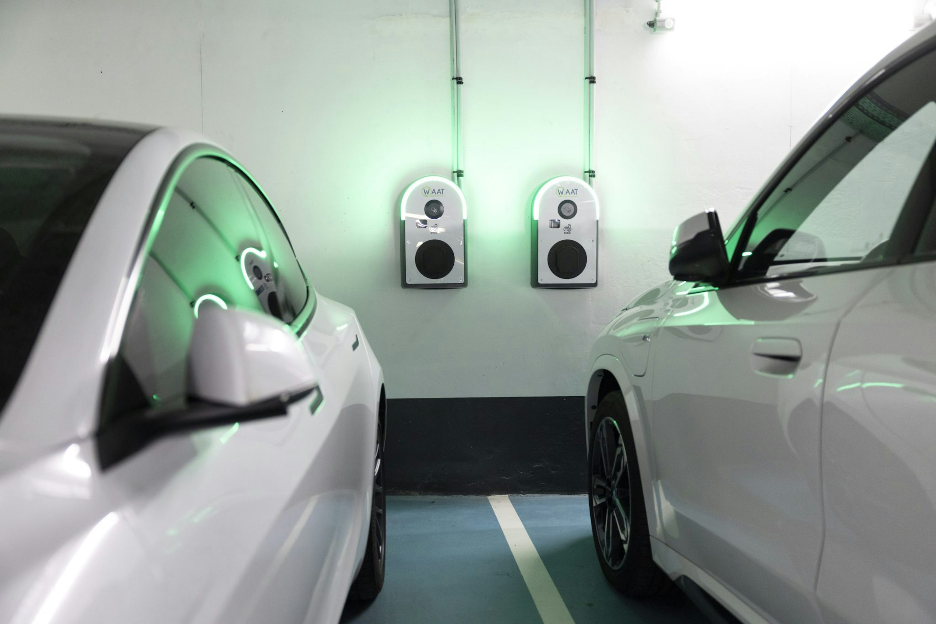 A picture of two electric cars parked near a Waat charging point